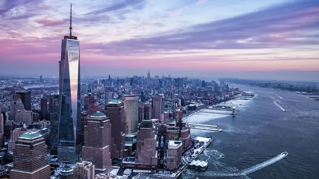 One World Trade Center rising above Lower Manhattan beside the Hudson River at dusk