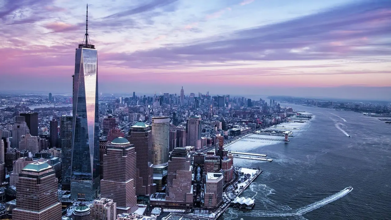 One World Trade Center rising above Lower Manhattan beside the Hudson River at dusk