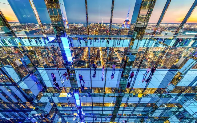 Mirrored floors and ceiling reflecting visitors and the Manhattan skyline inside SUMMIT One Vanderbilt